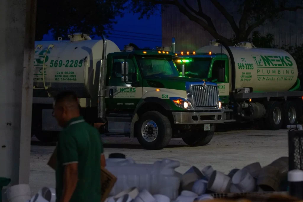 Meeks large septic trucks with employee walking in foreground